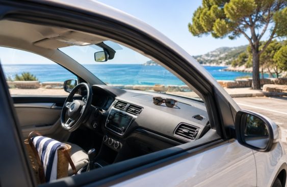 Célandine_Rigoulot_vacances-ete-code-de-la-route Intérieur d'une voiture avec vue sur la mer et des arbres en arrière-plan.